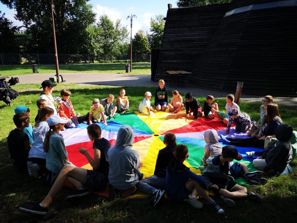 Widok na wigwam i dzieci w czasie zajęć z kolorową chustą